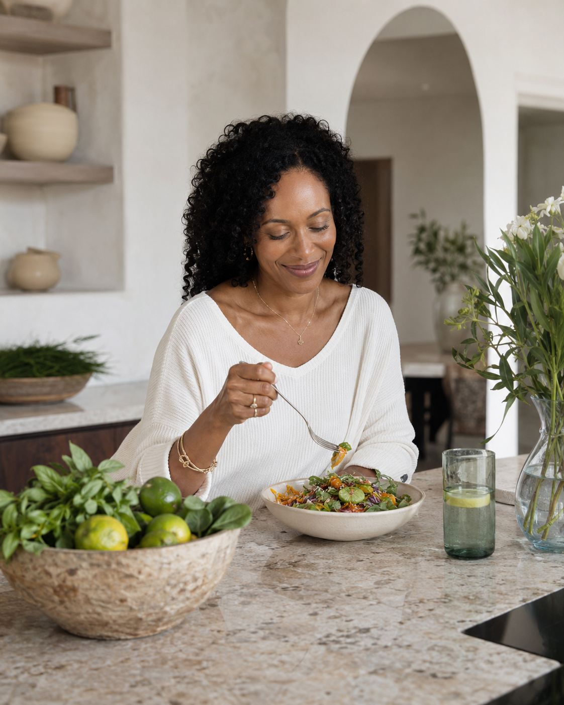 Woman enjoying a fresh, colorful salad in a bright kitchen